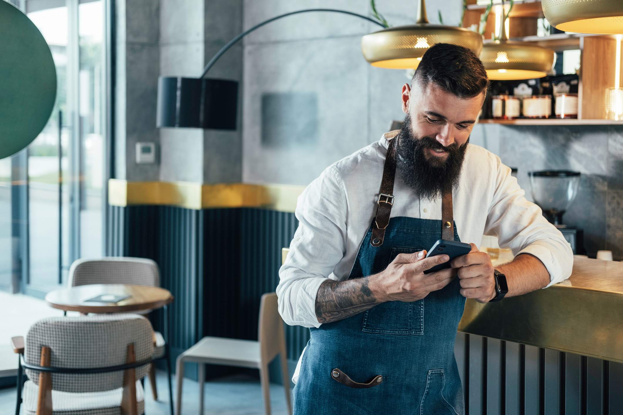 Image depicts a person leaning on a restaurant counter and utilizing their mobile phone.